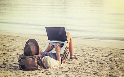 [Translate to Englisch:] Mann mit Laptop am Strand